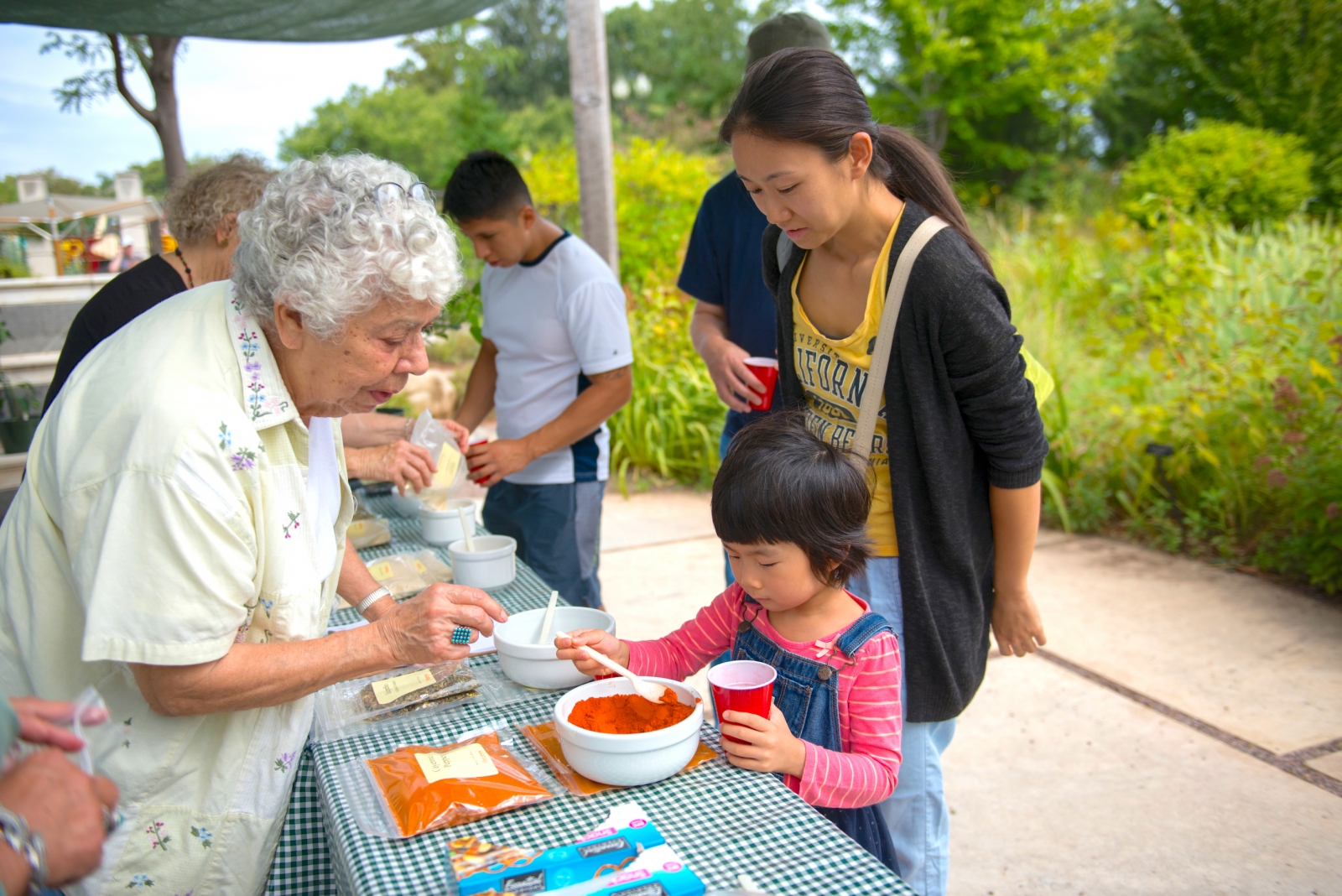 Child makes her own spice blend with the help over a woman volunteering during a festival