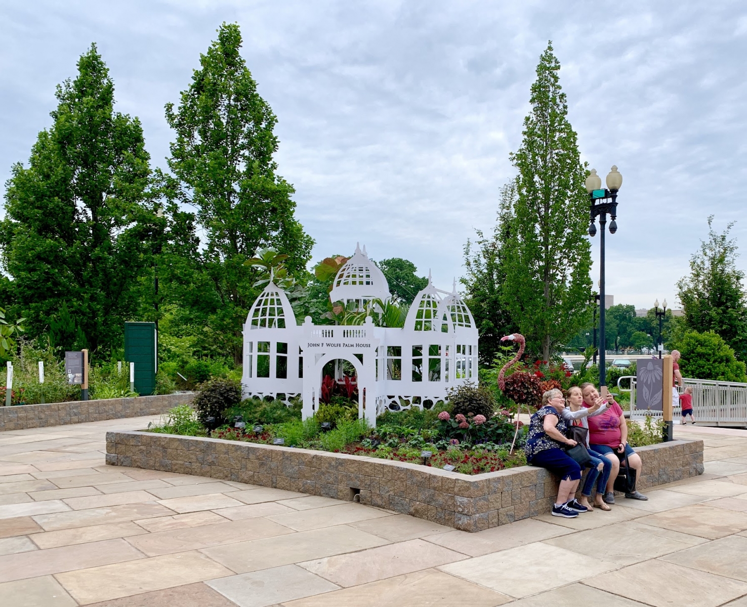 Visitors pose for a selfie with a flamingo topiary in the new exhibit