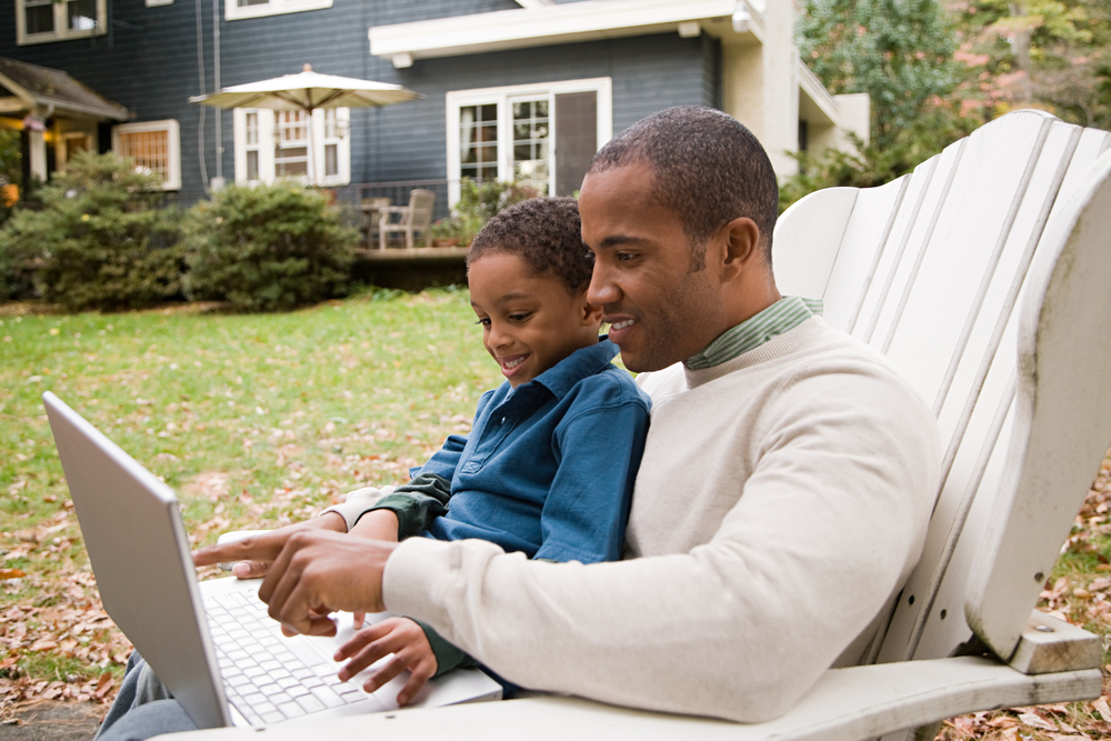 Father and son with computer outside