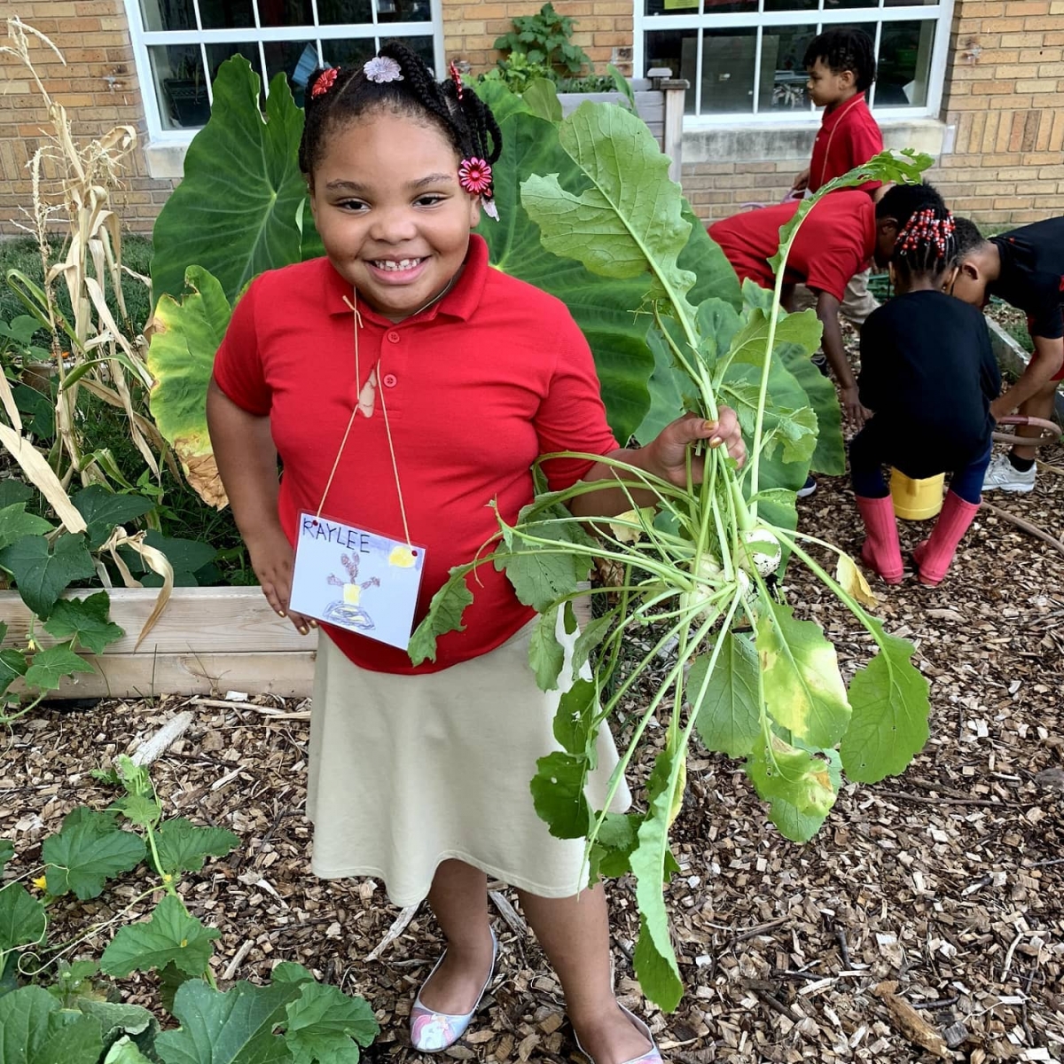 A child shows off produce she has picked from a farm at the Washington Youth Garden