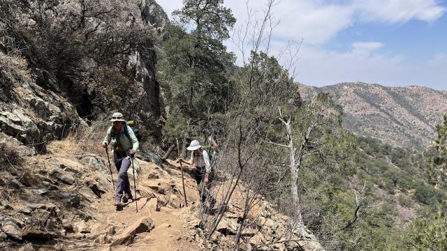 Two people hike up a dry mountain