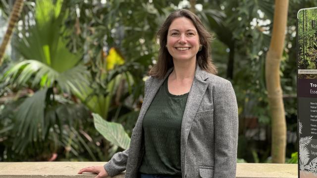 A woman stands in front of tropical plants in a Conservatory