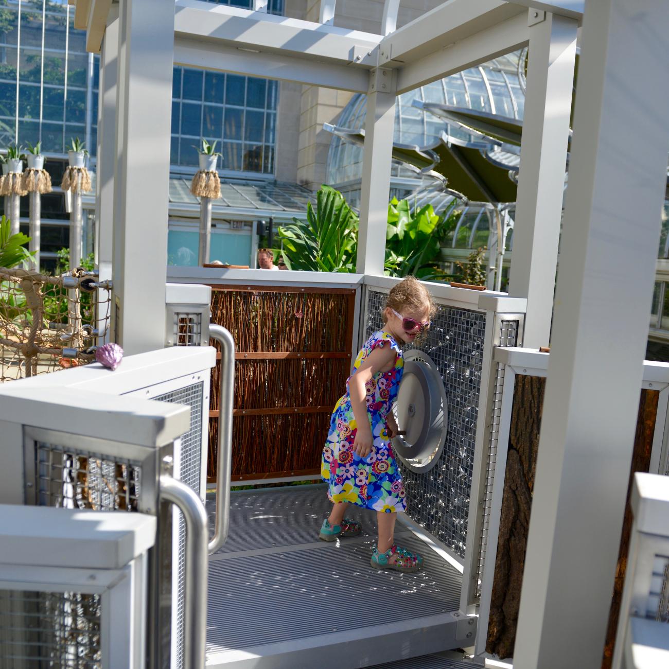 A child turns a crank in a play structure