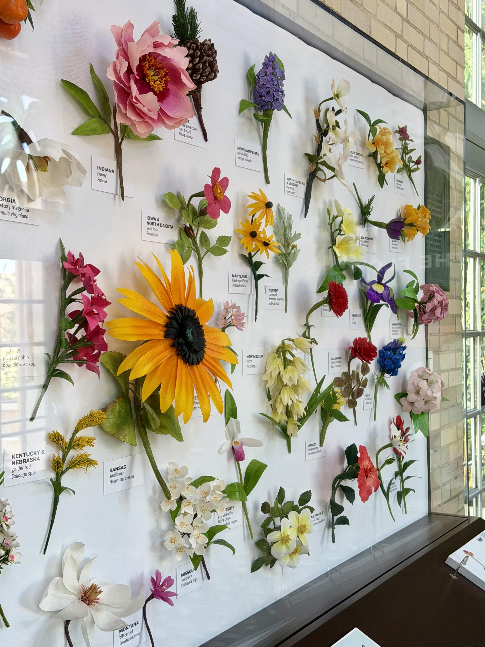 Artist-created flowers made from paper include a yellow sunflower, red rose, red carnation, and dozens more