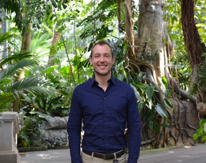 Devin Dotson stands in greenhouse of tropical plants